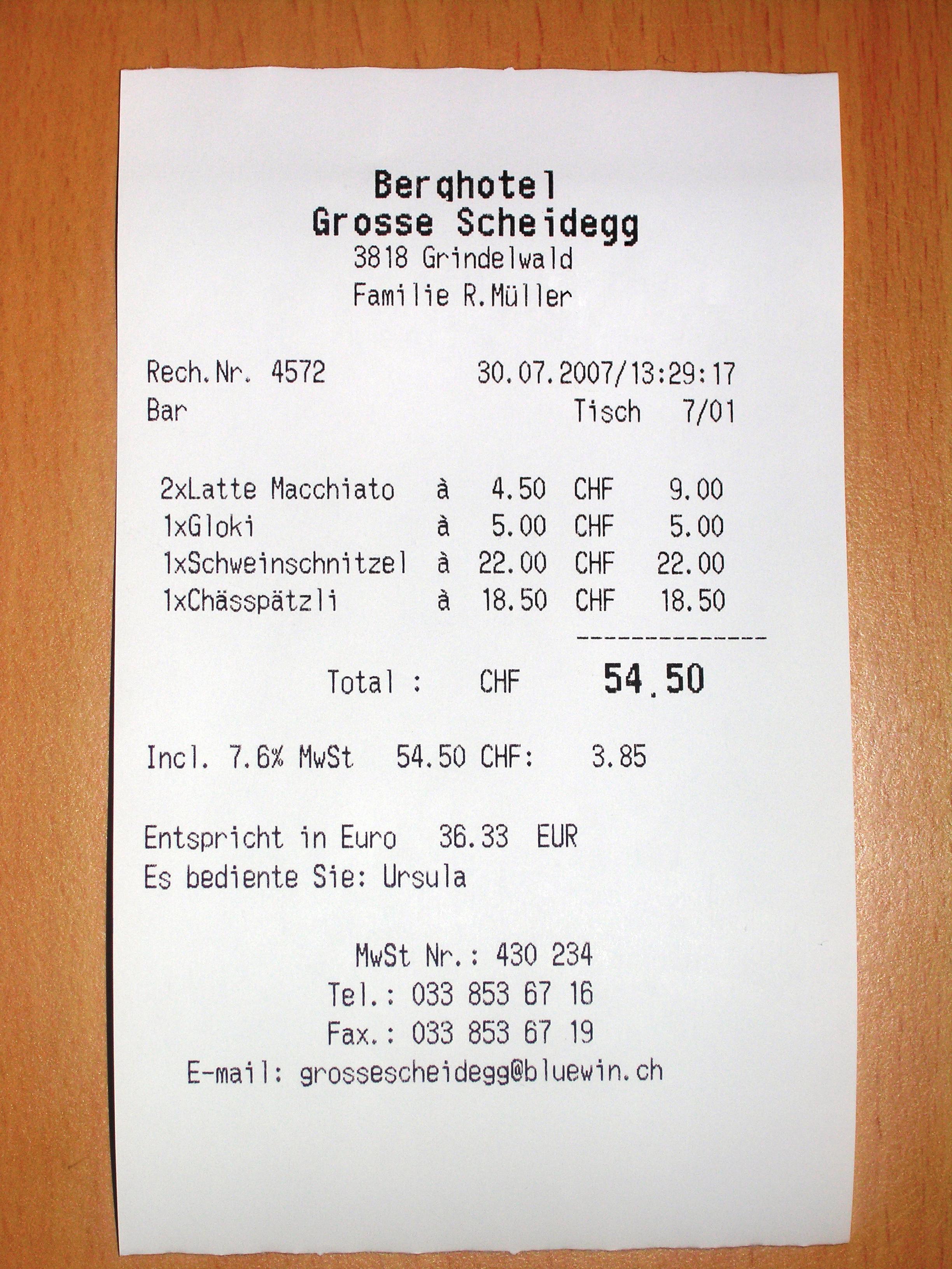 A printed paper receipt resting on a wooden table in soft light.